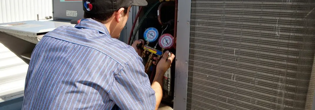 HVAC technician servicing a condenser unit in Ridgeway